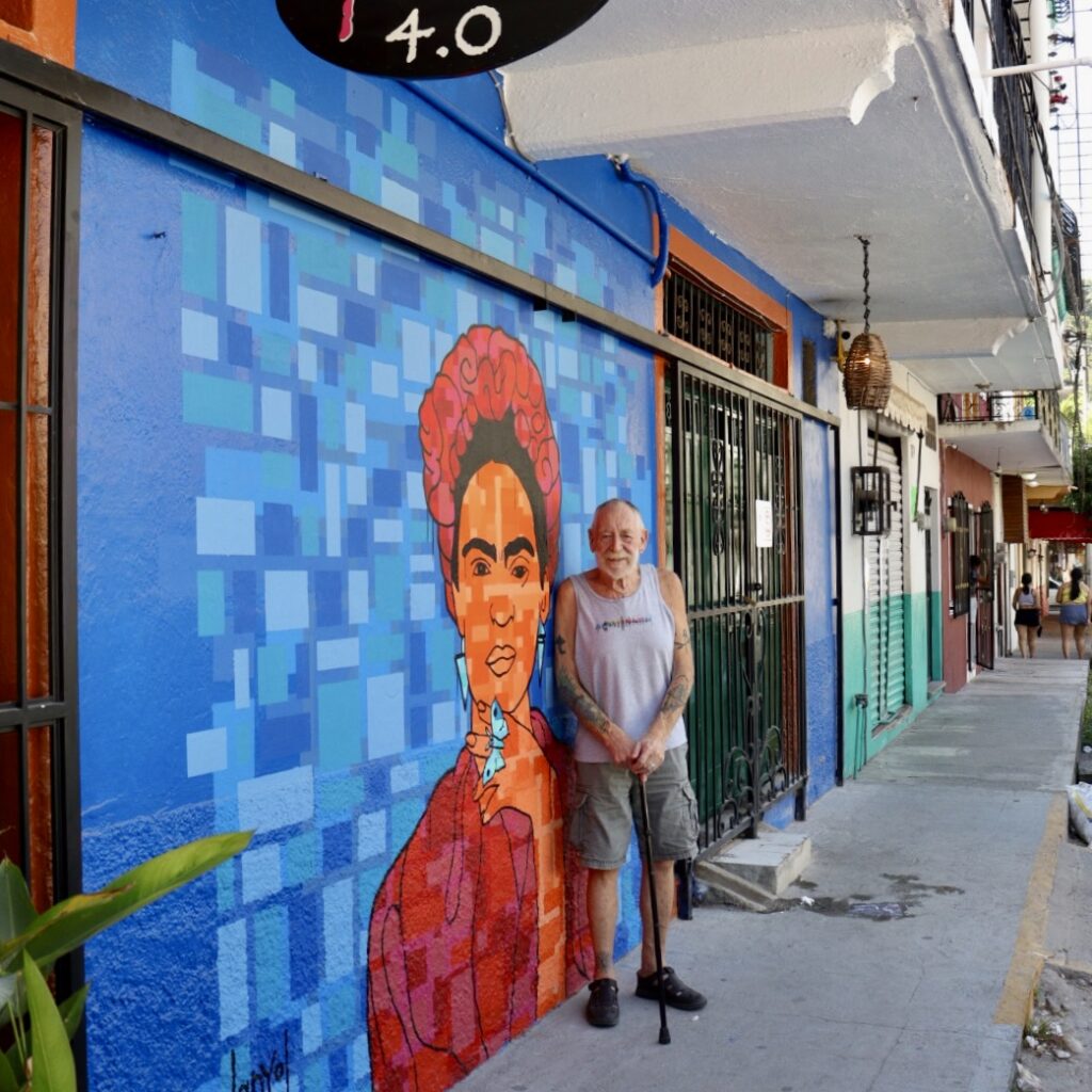 Tom Finely, propietario del Bar Frida 4.0, delante del mural inspirado en Frida y pintado por Tamale Ringwald.