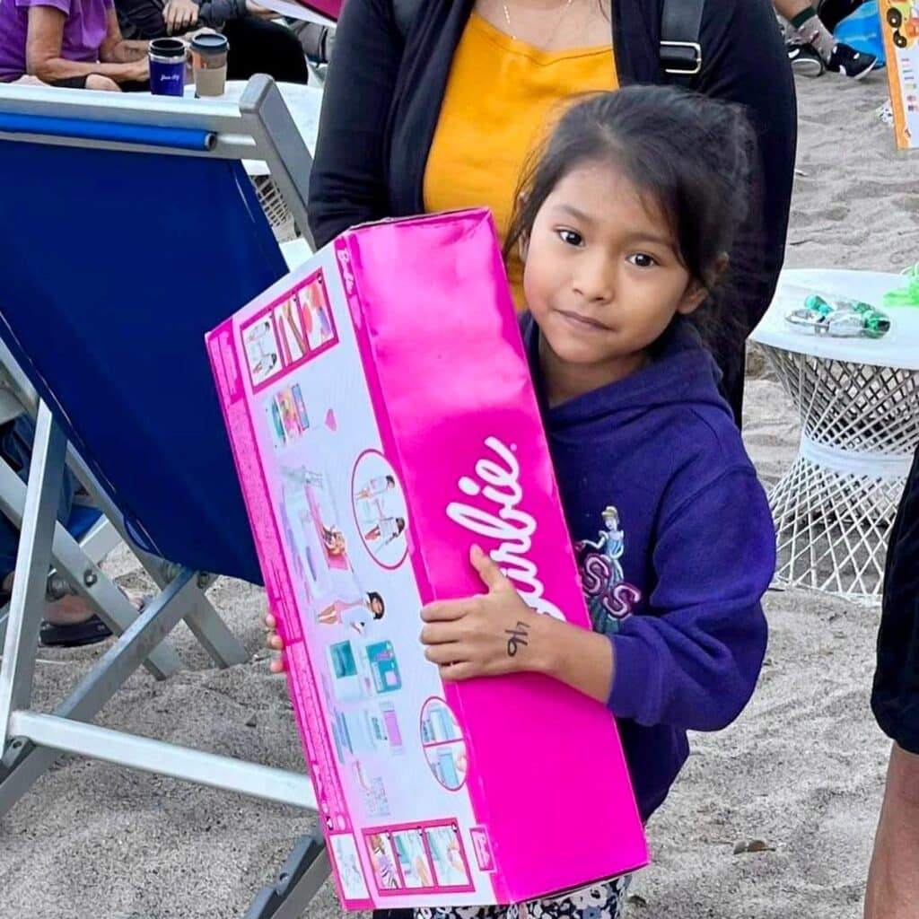 Una antigua tradición continuó esta mañana de Navidad en la playa, frente al bar, restaurante y hotel Blue Chairs. John Ramsey captó estas sonrisas de felicidad cuando los niños pudieron elegir un regalo de Navidad colgado de las palmeras.