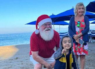 Navidad en la playa, al estilo de Puerto Vallarta Una antigua tradición continuó esta mañana de Navidad en la playa, frente al bar, restaurante y hotel Blue Chairs. John Ramsey captó estas sonrisas felices cuando los niños pudieron elegir un regalo de Navidad colgado de las palmeras.