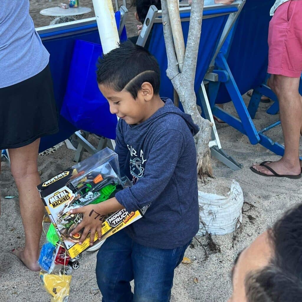 Una antigua tradición continuó esta mañana de Navidad en la playa, frente al bar, restaurante y hotel Blue Chairs. John Ramsey captó estas sonrisas de felicidad cuando los niños pudieron elegir un regalo de Navidad colgado de las palmeras.